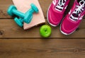 Sneakers dumbbells bottle of water and apple on wooden table Royalty Free Stock Photo