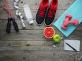sneakers dumbbells pomelo bottle of water apple and measure tape on old wooden table background Royalty Free Stock Photo