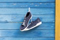 Sneakers hang on nail on colored wooden wall. Royalty Free Stock Photo