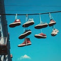 Sneakers hanging from wires against a blue sky.