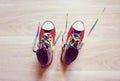 Sneakers LGBT colors with multicolored Shoestring. Fashionable shoes with untied shoelaces on wooden background.