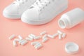 Sneakers and pills. Supportive drugs for the activities. Chondroitin capsules and training shoes. pink background Royalty Free Stock Photo