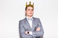 Sneering young handsome man wearing suit and crown keeping arms crossed Royalty Free Stock Photo