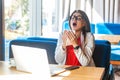 Sneeze, cold, influenza or allergies. Portrait of sick stylish brunette young woman in glasses sitting holding tissue napkin and Royalty Free Stock Photo