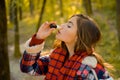 Sneezing young girl with nose wiper among yellow trees in park. Young woman blowing nose at nature. Woman makes a cure Royalty Free Stock Photo