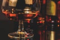 Snifter of brandy in elegant typical cognac glass in front of bottles in background