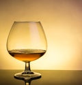 Snifter of brandy in elegant typical cognac glass on table with reflection Royalty Free Stock Photo