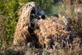 Sniper in ghillie suit with precision rifle with optic sight