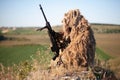 Sniper in ghillie suit with precision rifle with optic sight