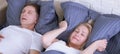 Snoring man. Couple in bed, man snoring and woman can not sleep, covering ears with pillow for snore noise. Middle age Royalty Free Stock Photo