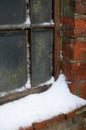 Snow accumulating on a brick wall and wooden window frame in a cold winter environment Royalty Free Stock Photo