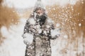 Snow in air on background of blurred image of stylish happy woman in knitted gloves in winter park. Winter time. Young hipster