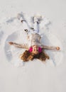 Snow angel made by a kid in the snow. Child girl playing and making a snow angel in the snow. Royalty Free Stock Photo