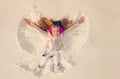 Snow angel made by a kid in the snow. Smiling child lying on snow with copy space. Funny kid making snow angel.