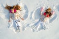 Snow angels made by a kids in the snow. Smiling children lying on snow with copy space. Funny kids making snow angel