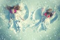 Snow angels made by a kids in the snow. Smiling children lying on snow with copy space. Funny kids making snow angel