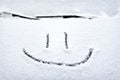 Snow background. Texture of wet snow with a cheerful smiley symbol pattern in the winter window of the car outdoors close-up. Royalty Free Stock Photo