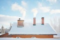 snow blanket on slanted roof with multiple smoking chimneys