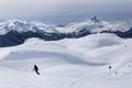 Snow capped mountain vista of Black Tusk and skiers on Whistler, BC.