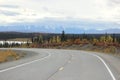 SNOW CAPPED ROCKY MOUNTAINS FALL FORREST AND CURVED HIGHWAY