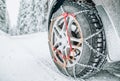 Snow chains on tire of car on snowy road in winter Royalty Free Stock Photo