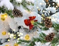 Snow Christmas tree branch and cones  with garland blurred  festive light and red folium bow in winter forest Royalty Free Stock Photo