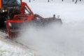 Snow cleaning. Snow removal tractor clearing snow from pavement with special round spinning brush, Royalty Free Stock Photo