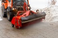 Snow cleaning. Snow removal tractor clearing snow from pavement with special round spinning brush, Royalty Free Stock Photo