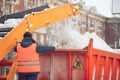 Snow cleaning tractor snow-removal machine loading pile of snow on a dump truck. Snow plow outdoors cleaning street city