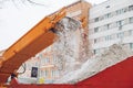 Snow cleaning tractor snow-removal machine loading pile of snow on a dump truck. Snow plow outdoors cleaning street city