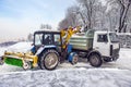 Snow cleaning tractor snow-removal machine loading pile of snow on a dump truck