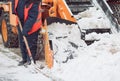 Snow cleaning tractor snow-removal machine loading pile of snow on a dump truck. Snow plow outdoors cleaning street city