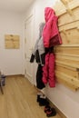 Snow clothes hanging on a hanger on the wall and boots on the floor in the entrance hall of the holiday apartment