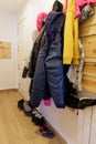 Snow clothes hanging on a hanger on the wall and boots on the floor in the entrance hall of the holiday apartment