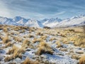 Snow covered Alpine grassland with wintery mountain range in the South Island of New Zealand in the afternoon light