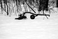 Snow covered antique plow next to a Wisconsin forest in winter