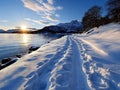 A snow covered beach with footprints in the snow near a body of water Royalty Free Stock Photo