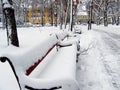 Snow-covered bench in city park at winter day. Beautiful winter photo Royalty Free Stock Photo