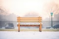 snow-covered bench in misty morning