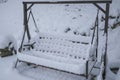 Snow covered bench in park/on the backyard close-up. Snowstorm. Winter weather