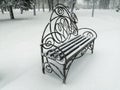 A snow-covered bench in the park. A beautiful bench in the snow. Snowy day - bench in the park in the snow. Royalty Free Stock Photo
