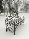 A snow-covered bench in the park. A beautiful bench in the snow. Snowy day - bench in the park in the snow. Royalty Free Stock Photo