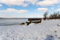 A snow covered bench with a view to the beach and River Deben at the popular visitor Bawdsey Quay on the Suffolk coast Royalty Free Stock Photo