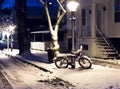 A snow covered bicycle at night under a lamppost