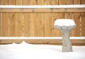 Snow covered birdbath in front of fence