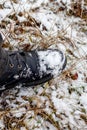 Snow-covered black boot of a man on his feet while walking in a winter park, top view. Man in black boots in the snow Royalty Free Stock Photo