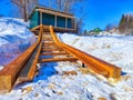 Snow-Covered Boat Launch Ramp With Adjacent Storage Shed. Wooden boat ramp with snow and a green storage shed Royalty Free Stock Photo