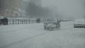 Snow-covered city road with cars in the snow