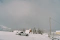 Snow-covered car stands on a hill in a small village in a mountain valley. Side view Royalty Free Stock Photo