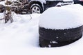 Snow-covered car tires. Summer tires in snowdrift of snow close-up.